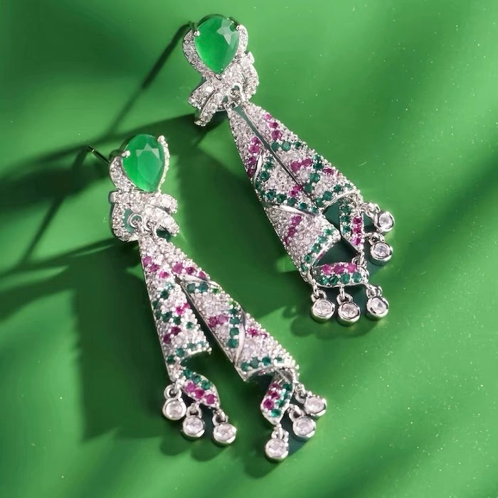 Emerald Ribbon Cascade Earrings with an emerald green teardrop crystal, silver-plated finish, sparkling zirconia, ribbon-inspired detailing, and crystal tassels.