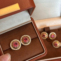 Vintage Style Halo Crystal Stud Earrings featuring a sparkling halo of zirconias surrounding a ruby red or sky blue center stone in a gold-tone vintage-inspired setting.
