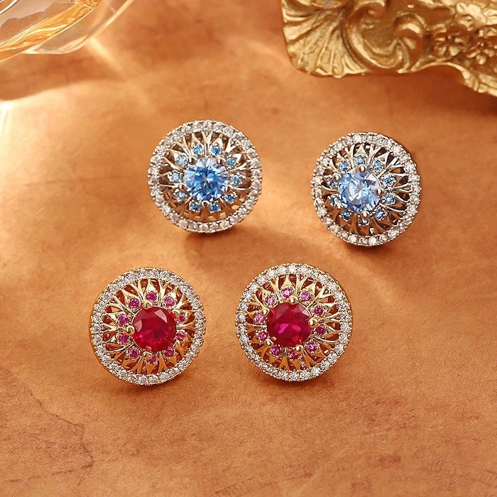 Vintage Style Halo Crystal Stud Earrings featuring a sparkling halo of zirconias surrounding a ruby red or sky blue center stone in a gold-tone vintage-inspired setting.
