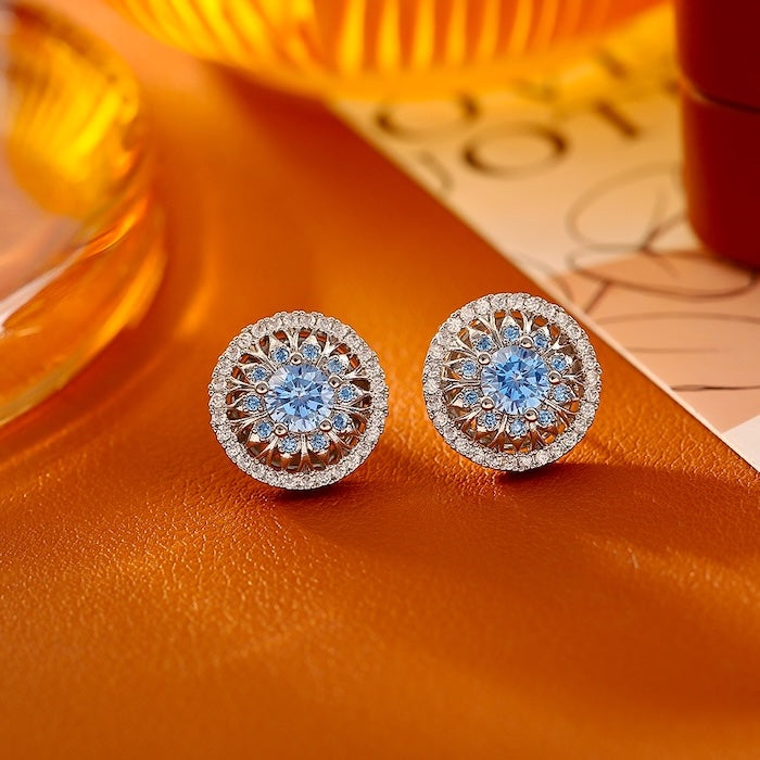 Vintage Style Halo Crystal Stud Earrings featuring a sparkling halo of zirconias surrounding a ruby red or sky blue center stone in a gold-tone vintage-inspired setting.
