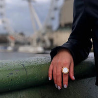 Vintage Mother of Pearl Dome Ring featuring a large round mother-of-pearl cabochon in a textured gold-tone adjustable setting worn as a statement ring.
