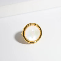 Vintage Mother of Pearl Dome Ring featuring a large round mother-of-pearl cabochon in a textured gold-tone adjustable setting worn as a statement ring.
