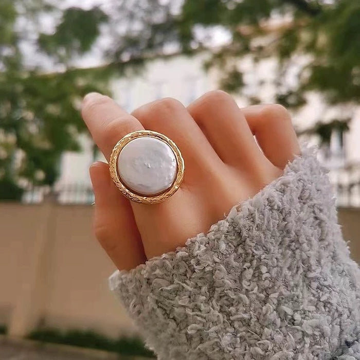 Vintage Mother of Pearl Dome Ring featuring a large round mother-of-pearl cabochon in a textured gold-tone adjustable setting worn as a statement ring.
