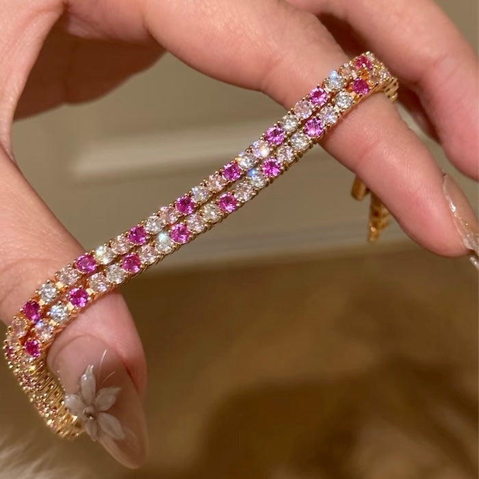 Dazzling Pink Ombré Tennis Bracelet featuring sparkling pink and clear zirconias in a gradient tennis bracelet design, available in two stone sizes.
