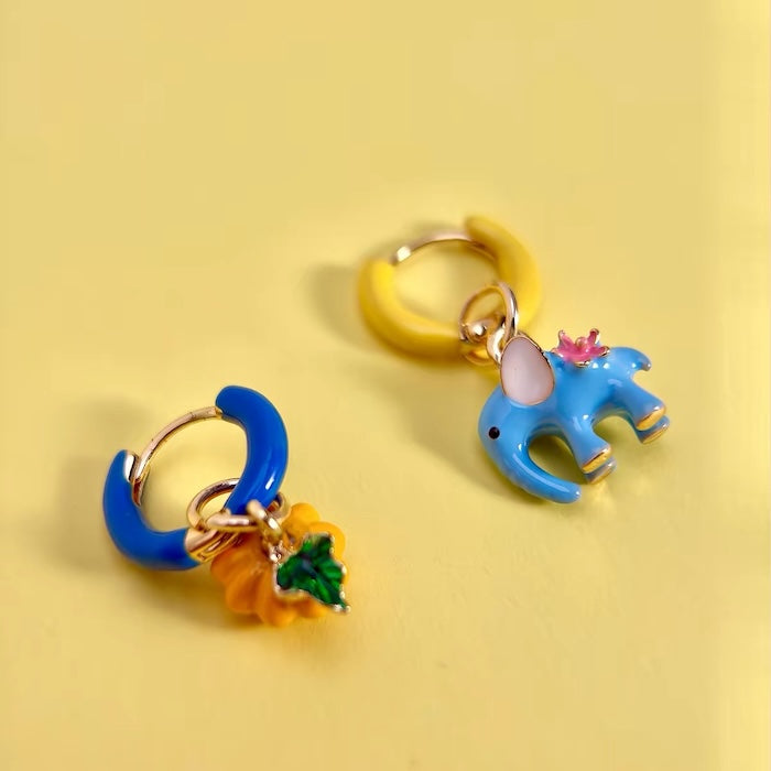 Enchanted Elephant & Pumpkin Enamel Hoop Earrings featuring a blue elephant charm and an orange pumpkin charm with vibrant hand-painted enamel on gold-plated brass hoops, measuring 3 × 1.5 cm.