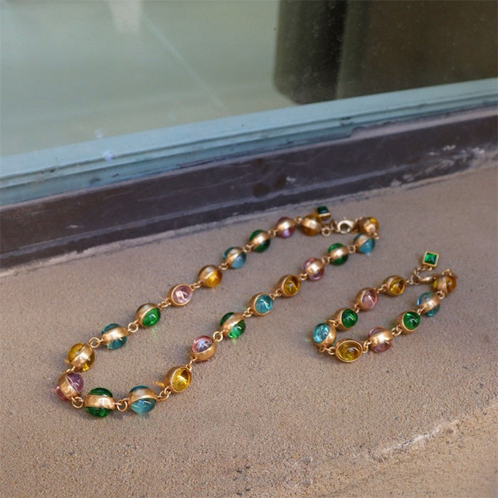 Vintage Rainbow Glass Stones Jewelry Set featuring multicolor glass stones in green, blue, pink, and amber tones linked in a gold-tone vintage-inspired necklace and bracelet design.
