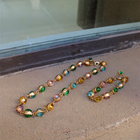 Vintage Rainbow Glass Stones Jewelry Set featuring multicolor glass stones in green, blue, pink, and amber tones linked in a gold-tone vintage-inspired necklace and bracelet design.
