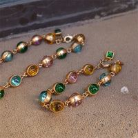 Vintage Rainbow Glass Stones Jewelry Set featuring multicolor glass stones in green, blue, pink, and amber tones linked in a gold-tone vintage-inspired necklace and bracelet design.

