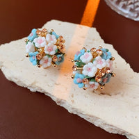 Blooming Rose Bouquet Ceramic Earrings featuring handcrafted ceramic roses, sparkling crystal accents, and rose gold-plated brass. Available in lilac or light blue for timeless vintage-inspired elegance.