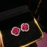 Vivid Ruby Flower Jewelry Set featuring ruby-red floral zirconias surrounded by sparkling crystal halos, including matching stud earrings and an adjustable ring.

