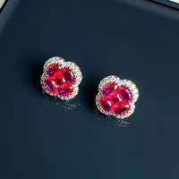 Vivid Ruby Flower Jewelry Set featuring ruby-red floral zirconias surrounded by sparkling crystal halos, including matching stud earrings and an adjustable ring.
