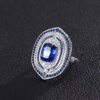 Royal Sapphire Halo Crystal Dress Ring in white gold-plated brass featuring a sapphire-blue center crystal with layered blue and clear crystal halos.
