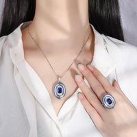 Royal Sapphire Halo Crystal Dress Ring in white gold-plated brass featuring a sapphire-blue center crystal with layered blue and clear crystal halos.
