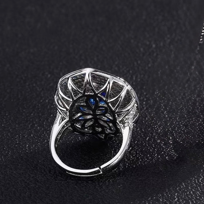 Royal Sapphire Halo Crystal Dress Ring in white gold-plated brass featuring a sapphire-blue center crystal with layered blue and clear crystal halos.
