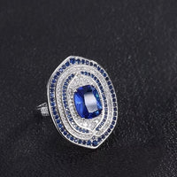Royal Sapphire Halo Crystal Dress Ring in white gold-plated brass featuring a sapphire-blue center crystal with layered blue and clear crystal halos.
