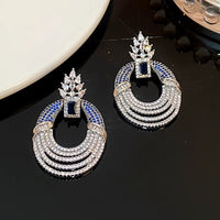 Royal Style Sapphire Look Oversized Earrings featuring sapphire-blue zirconias, sparkling pavé crystal details, and an elegant silver-tone statement design.
