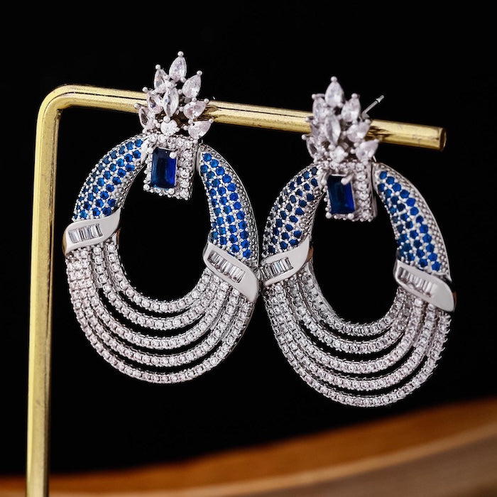 Royal Style Sapphire Look Oversized Earrings featuring sapphire-blue zirconias, sparkling pavé crystal details, and an elegant silver-tone statement design.
