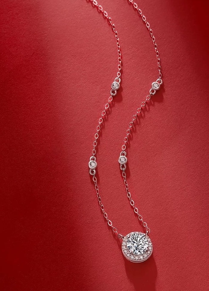 Star Halo Moissanite Necklace featuring a 1 ct round moissanite center stone surrounded by a sparkling halo, accented with bezel-set moissanite stones along a sterling silver chain.