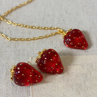 Sweet Strawberry Jewelry Set featuring glossy red strawberry stud earrings and a matching pendant necklace crafted in gold-plated brass with hand-finished resin enamel.
