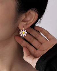 Golden Twin Daisy Hoop Earrings featuring one green enamel daisy and one soft pink enamel daisy suspended from polished gold-tone hoops.