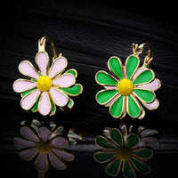 Golden Twin Daisy Hoop Earrings featuring one green enamel daisy and one soft pink enamel daisy suspended from polished gold-tone hoops.