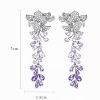 Dazzling Wisteria Flower Tassel Earrings featuring sparkling floral zirconia details and cascading lavender-toned crystal tassels in a silver-tone setting.
