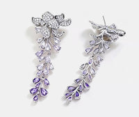 Dazzling Wisteria Flower Tassel Earrings featuring sparkling floral zirconia details and cascading lavender-toned crystal tassels in a silver-tone setting.
