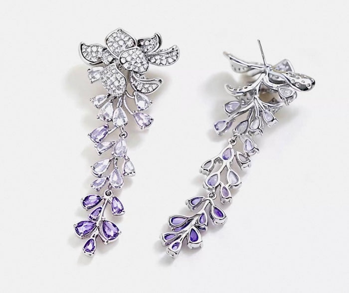 Dazzling Wisteria Flower Tassel Earrings featuring sparkling floral zirconia details and cascading lavender-toned crystal tassels in a silver-tone setting.
