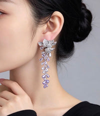 Dazzling Wisteria Flower Tassel Earrings featuring sparkling floral zirconia details and cascading lavender-toned crystal tassels in a silver-tone setting.
