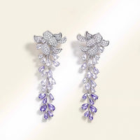 Dazzling Wisteria Flower Tassel Earrings featuring sparkling floral zirconia details and cascading lavender-toned crystal tassels in a silver-tone setting.
